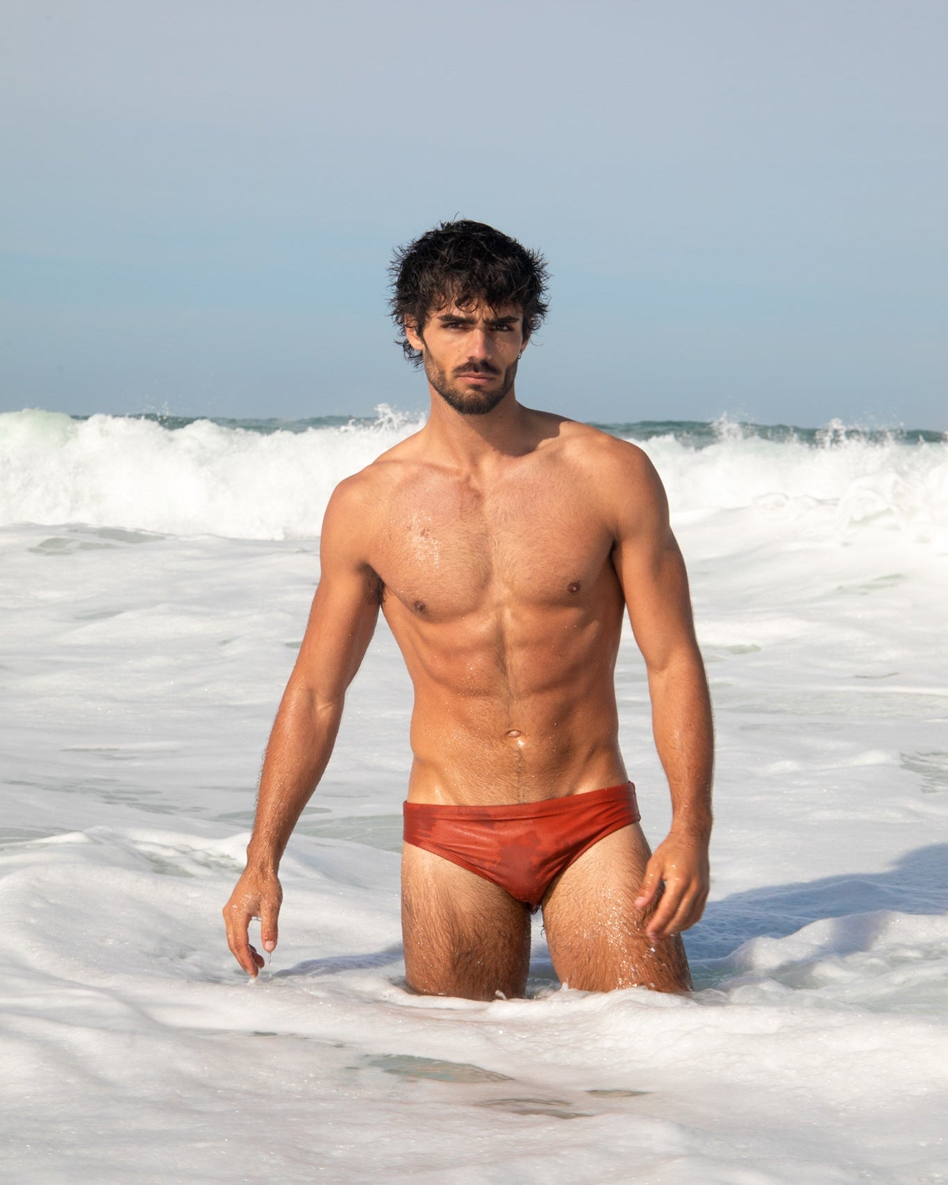 Man in red swim trunks standing in ocean waves