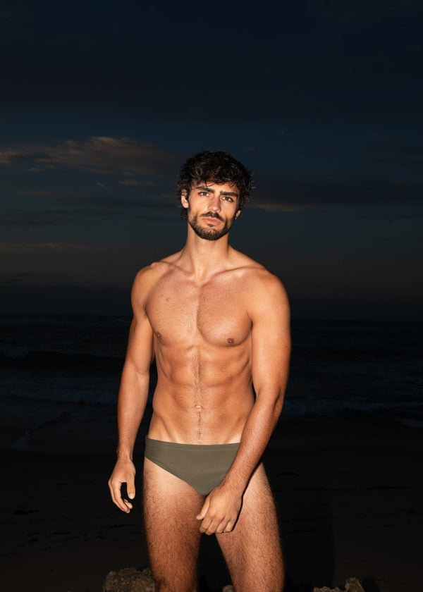 Man standing on a beach at dusk with a dark sky.