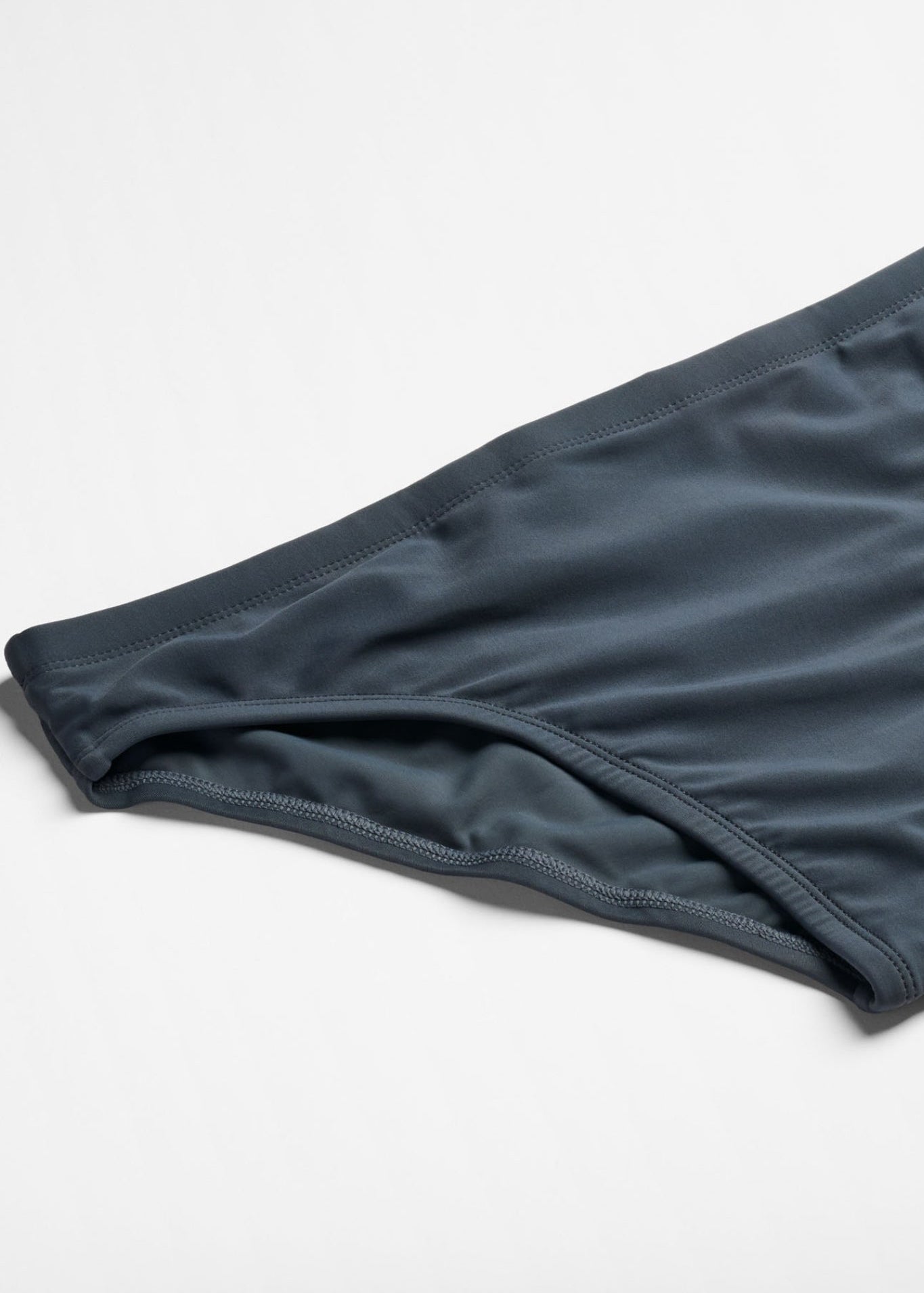 Dark blue swim briefs on a light gray background