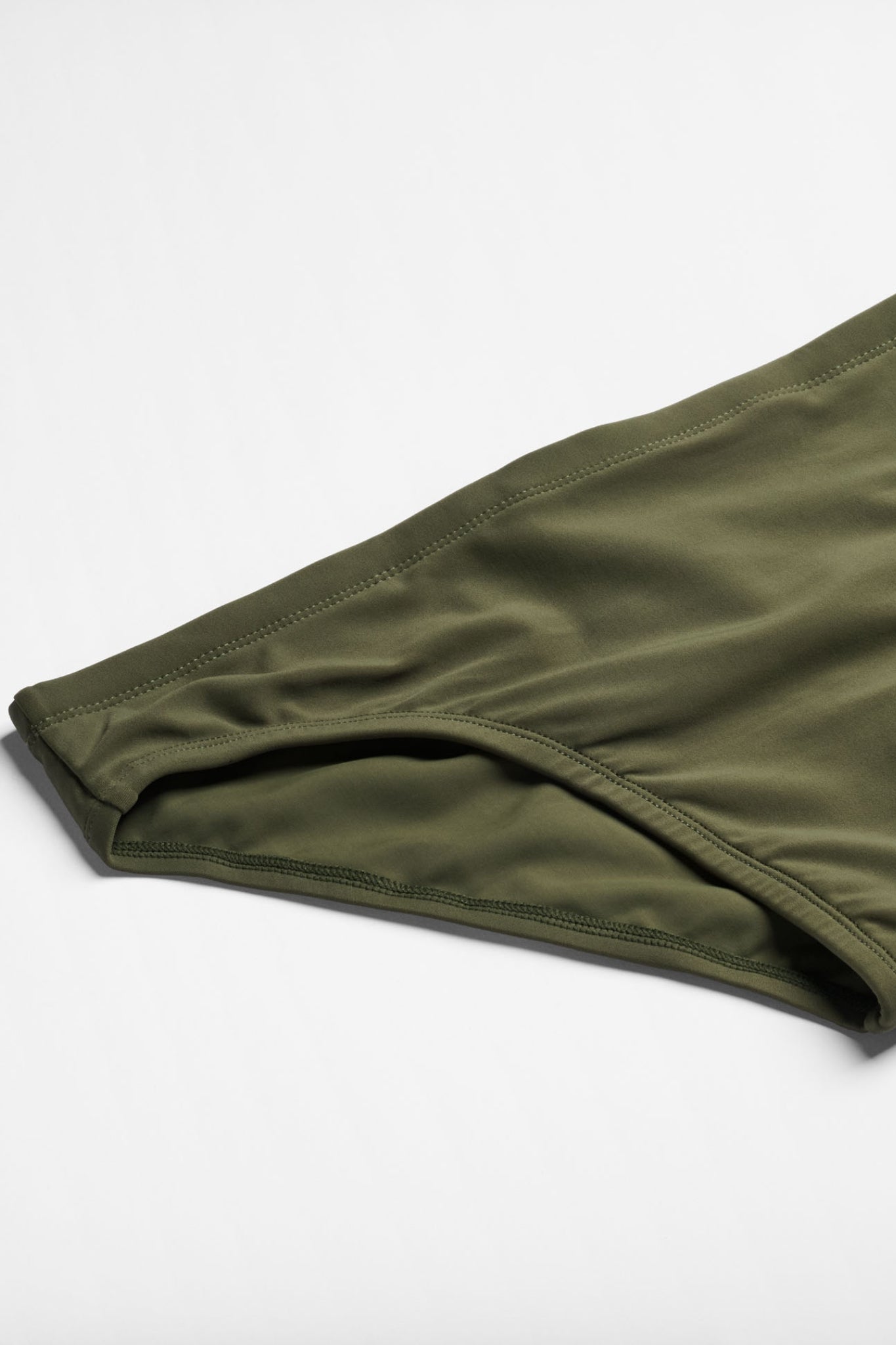 Green swim brief on a light gray background
